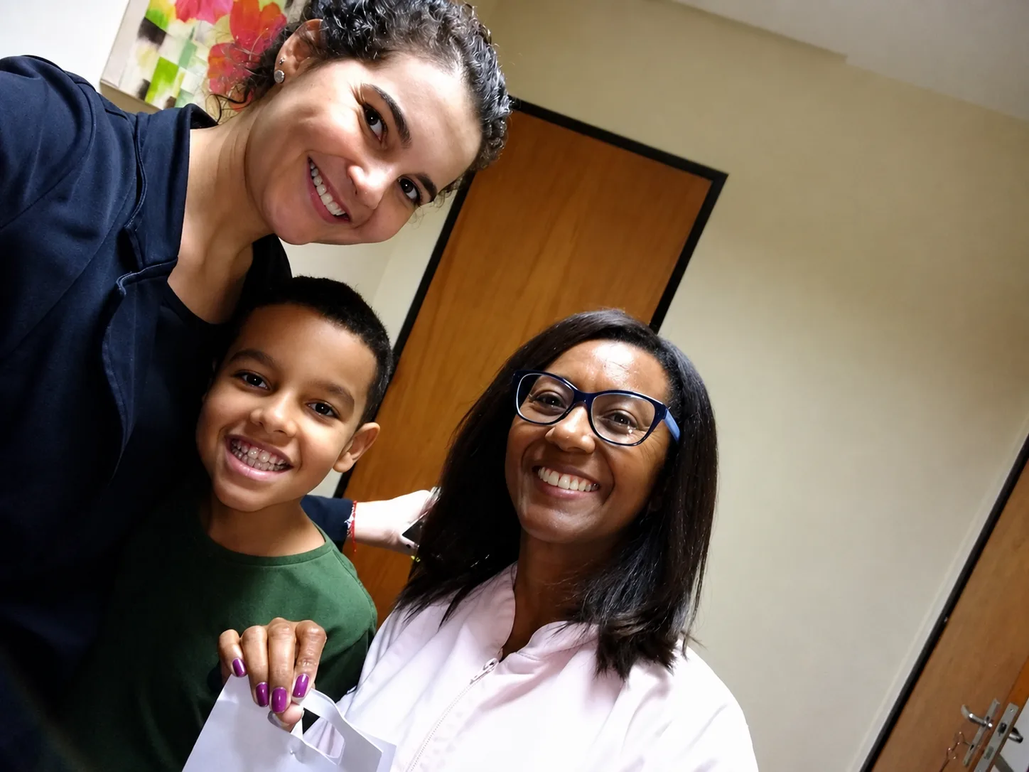 Elisangela, criança e mãe sorrindo após o atendimento